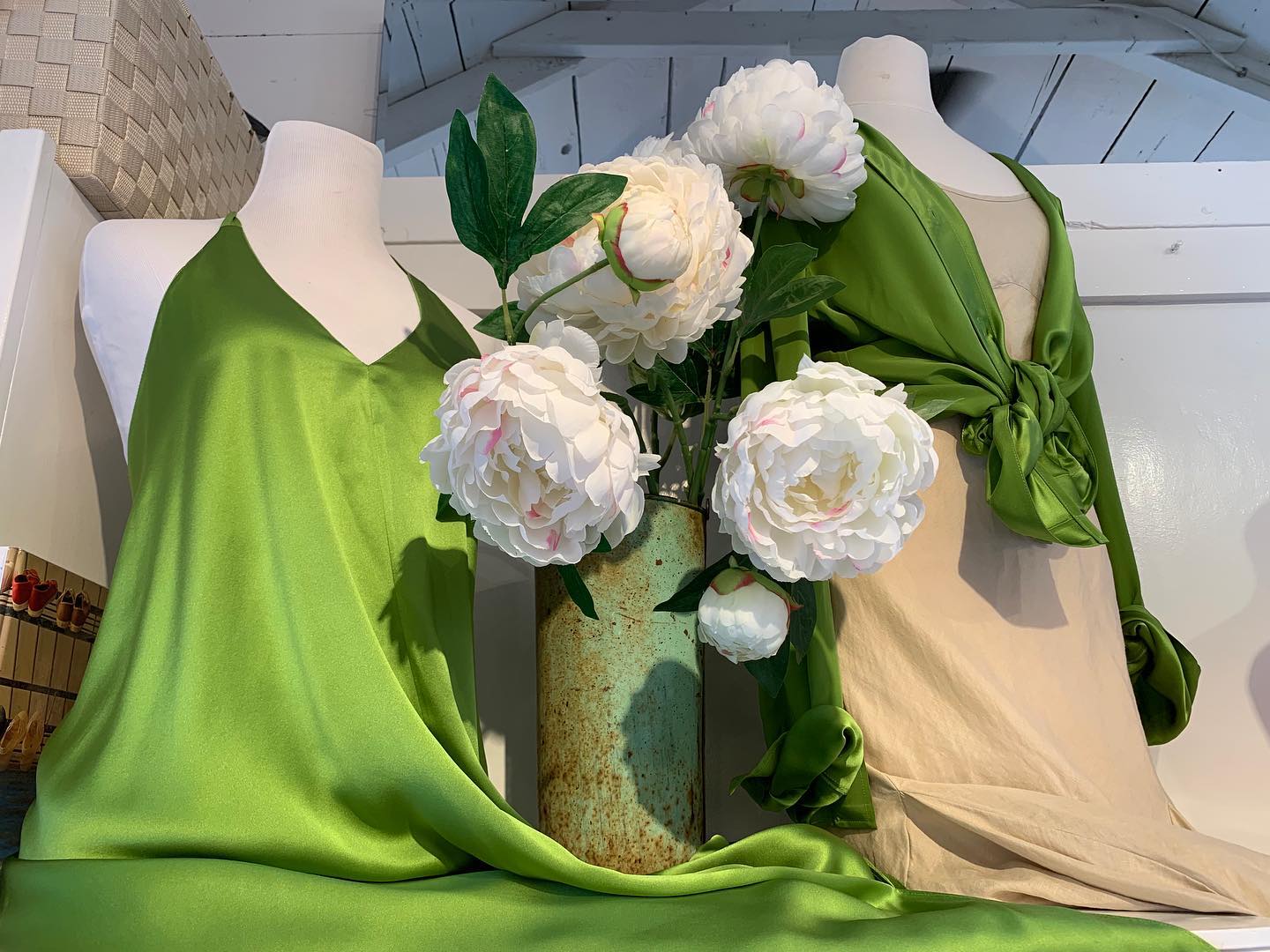 Washed silk in bright peony green and sand, knotted on dress forms beside white peonies